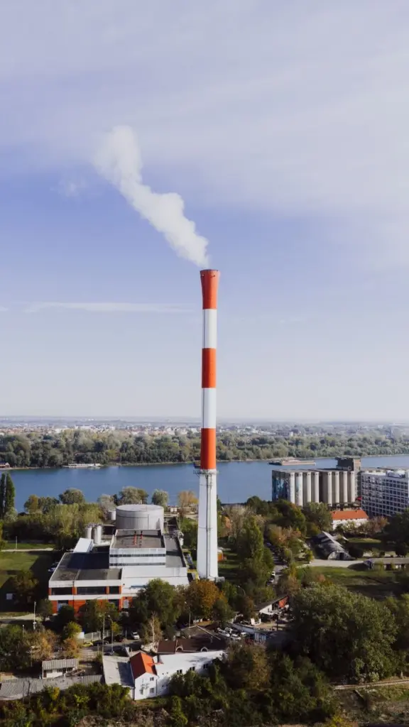 Aerial view of thermal power plant with smoke stack in Belgrade, Serbia against a clear blue sky.