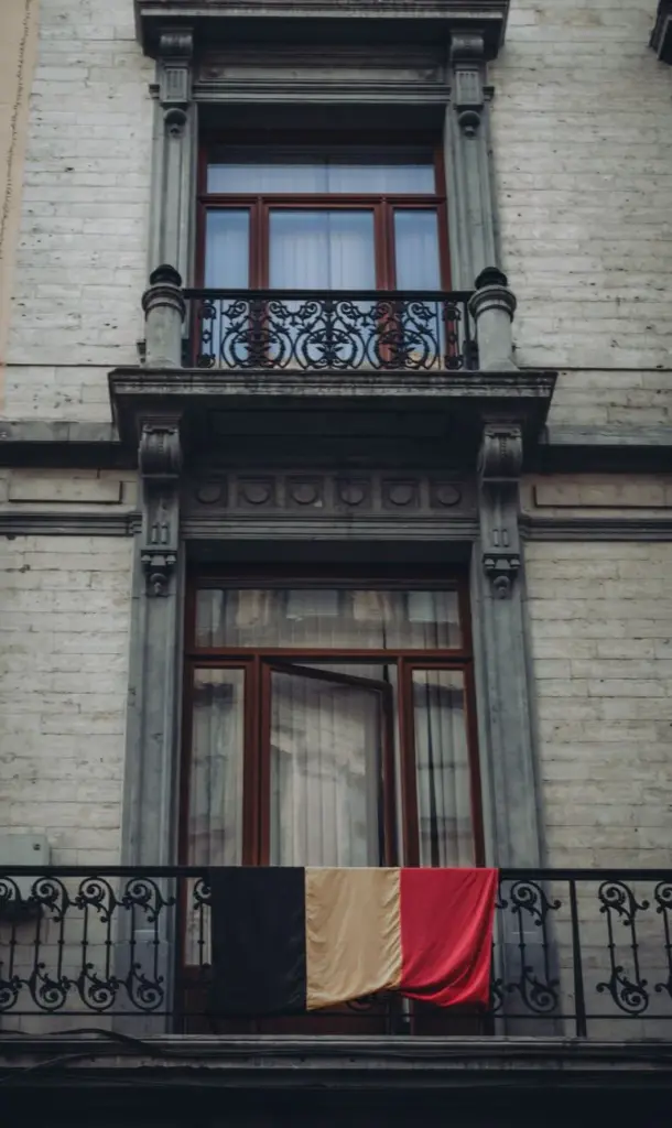 Close-up of historic building facade with Belgian flag draped on the balcony.