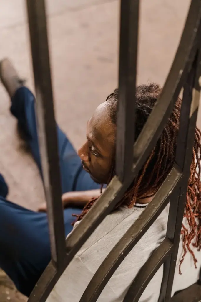 Rear view of a man sitting outdoors, captured candidly through a railing.