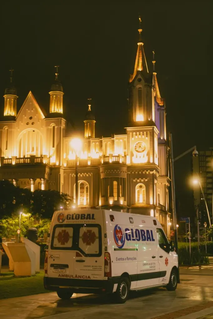 Majestic church illuminated at night with an ambulance in the foreground.