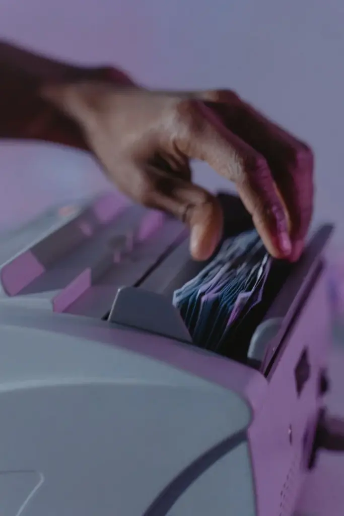 A hand operates a money counter, sorting banknotes efficiently.