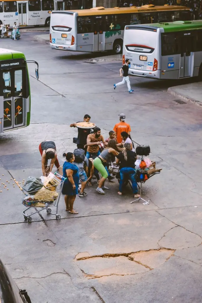 Street vendors selling goods near buses in a busy urban area.