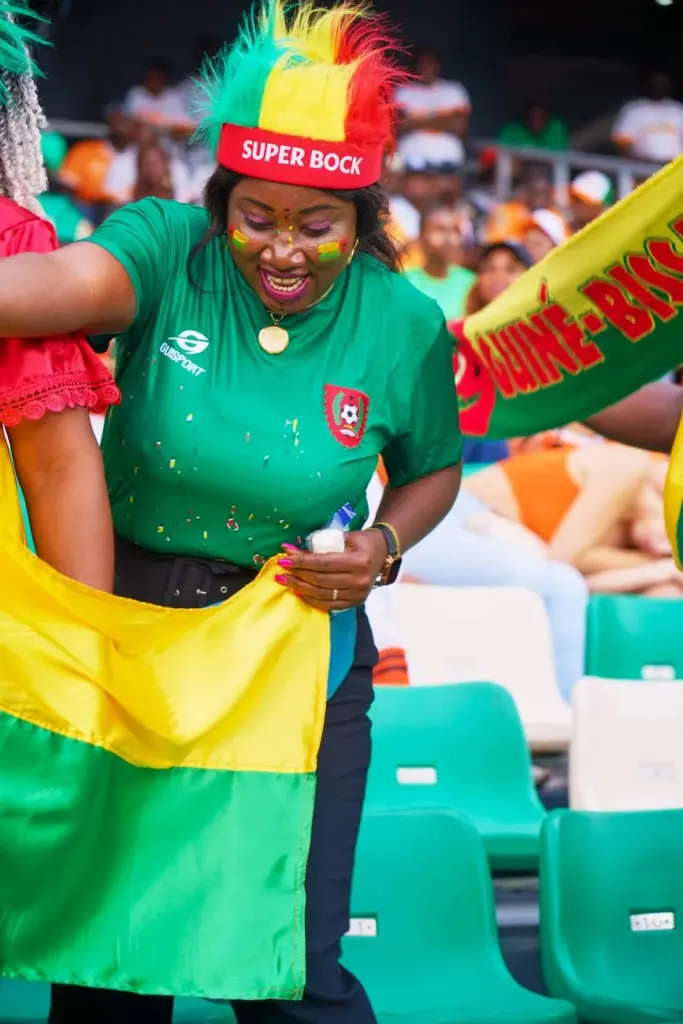 A woman enthusiastically supporting her team with face paint and colorful attire at a sports event.
